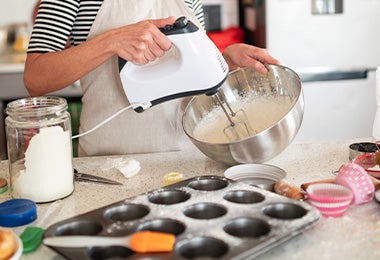 Mujer mezclando masa de muffins frente a una mesa con moldes de silicona