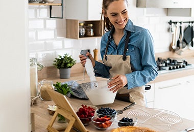 Mujer con ingredientes y preparando pavlova