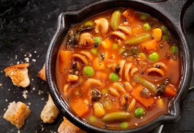 Sopa de pasta y verduras preparada en una olla de hierro