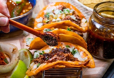 Tacos de birria con clavos de olor, cebolla y cilantro