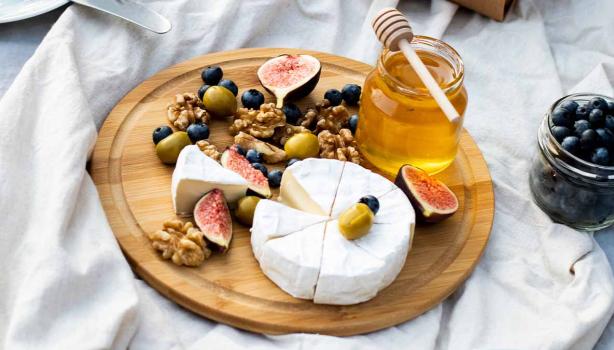 Tabla de quesos con miel, frutas y aceitunas