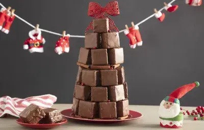 Fotografía en tonos rojos sobre un banco de madera con un pequeño tendedero de Papá Noel, un adorno de Papá Noel en el lado derecho, un plato pequeño con dos bollos y en el centro varios bollos formando un árbol de Navidad.